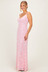 woman wearing a pink floral long dress with spaghetti straps and a fitted silhouette