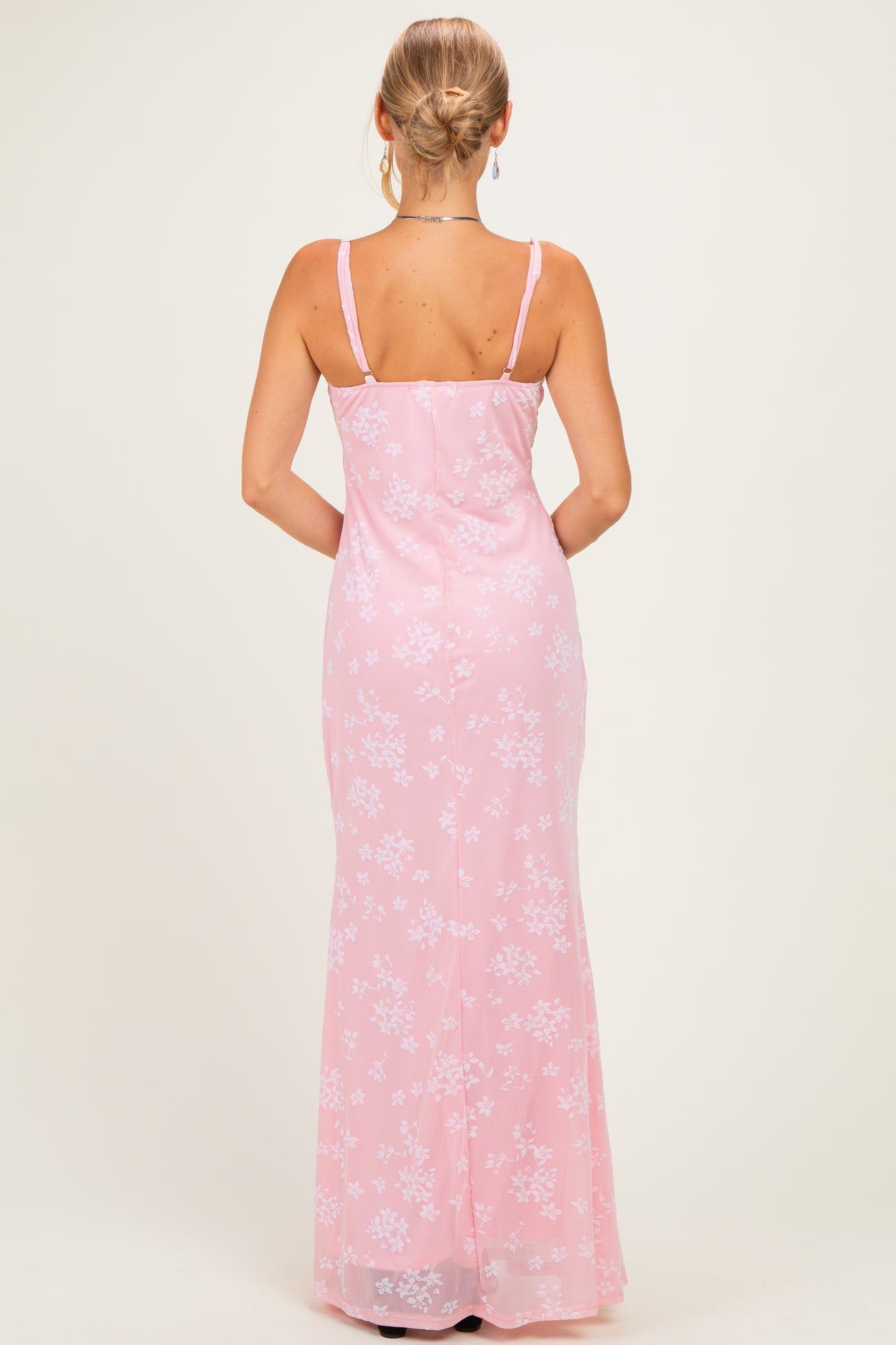 woman wearing a pink floral evening gown with a fitted silhouette and spaghetti straps, shown from the back