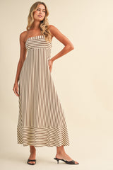 woman wearing a striped strapless maxi dress with a flared hem and black slide sandals