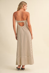 woman wearing a strapless cream and brown striped maxi dress with an open back and keyhole detail, standing sideways