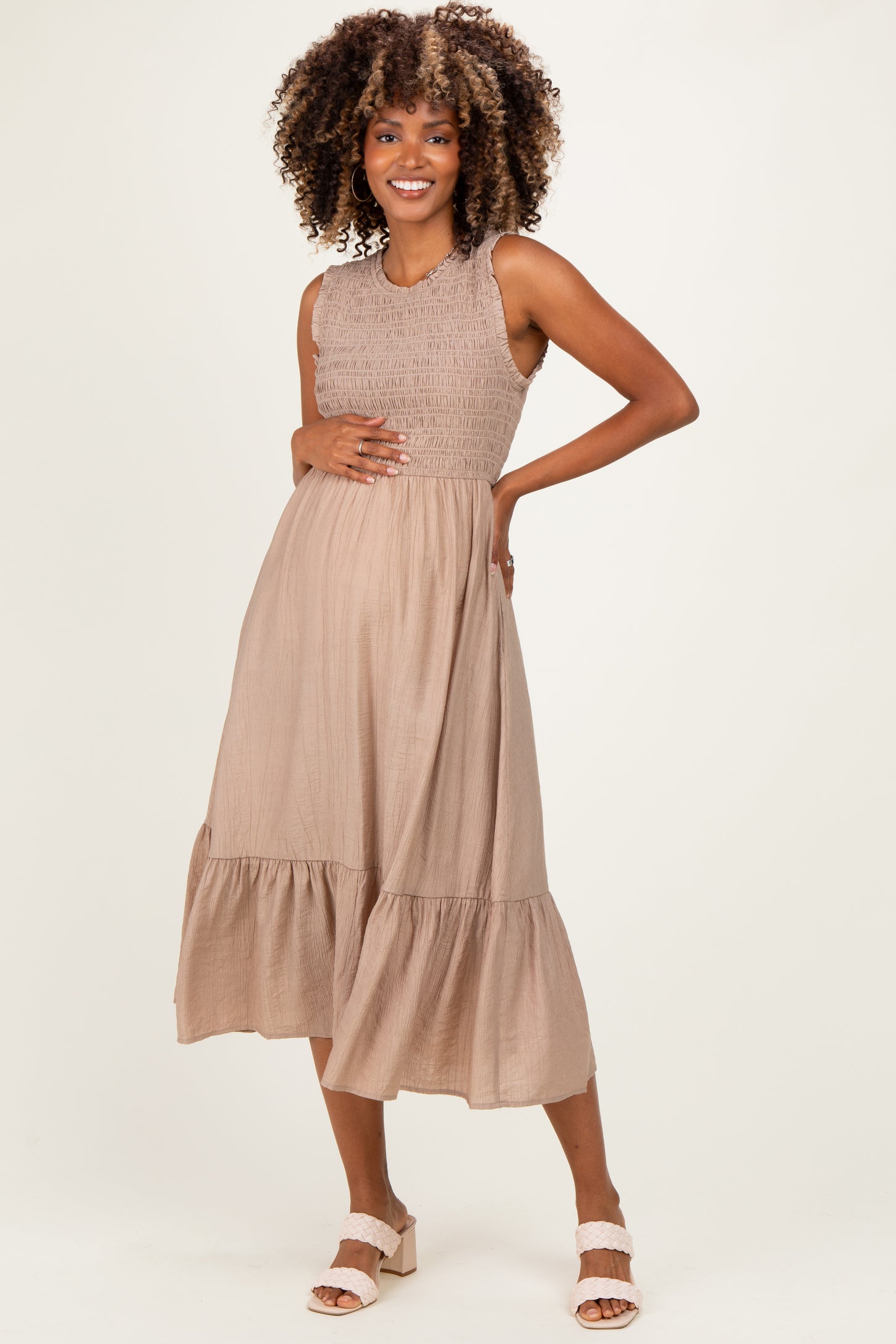 woman wearing a taupe maternity dress with smocked bodice and tiered hem, showcasing her baby bump