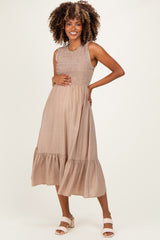 woman wearing a taupe maternity dress with smocked bodice and tiered hem, showcasing her baby bump