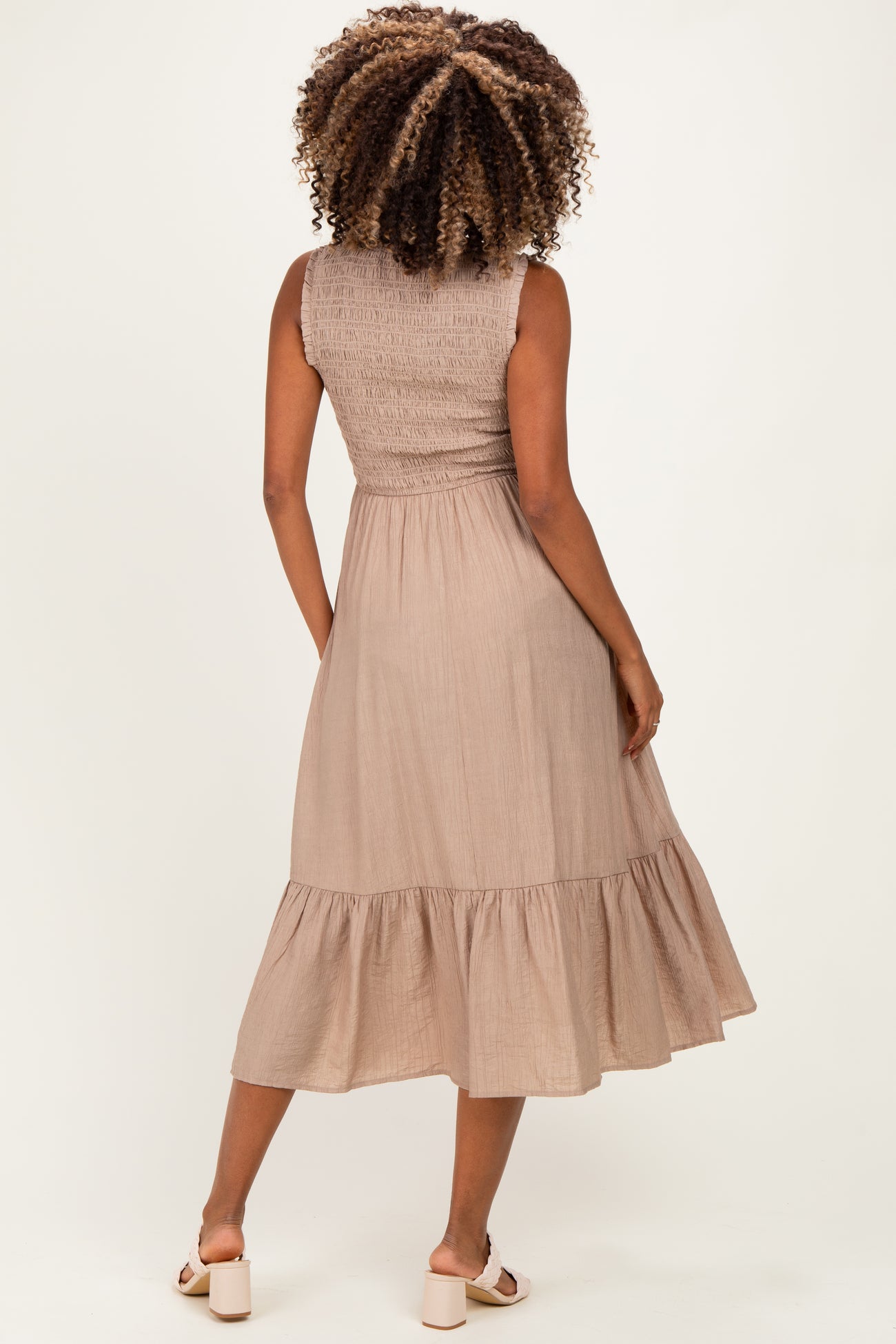 woman wearing a light brown maternity dress with a smocked bodice and tiered ruffle hem, showing her back
