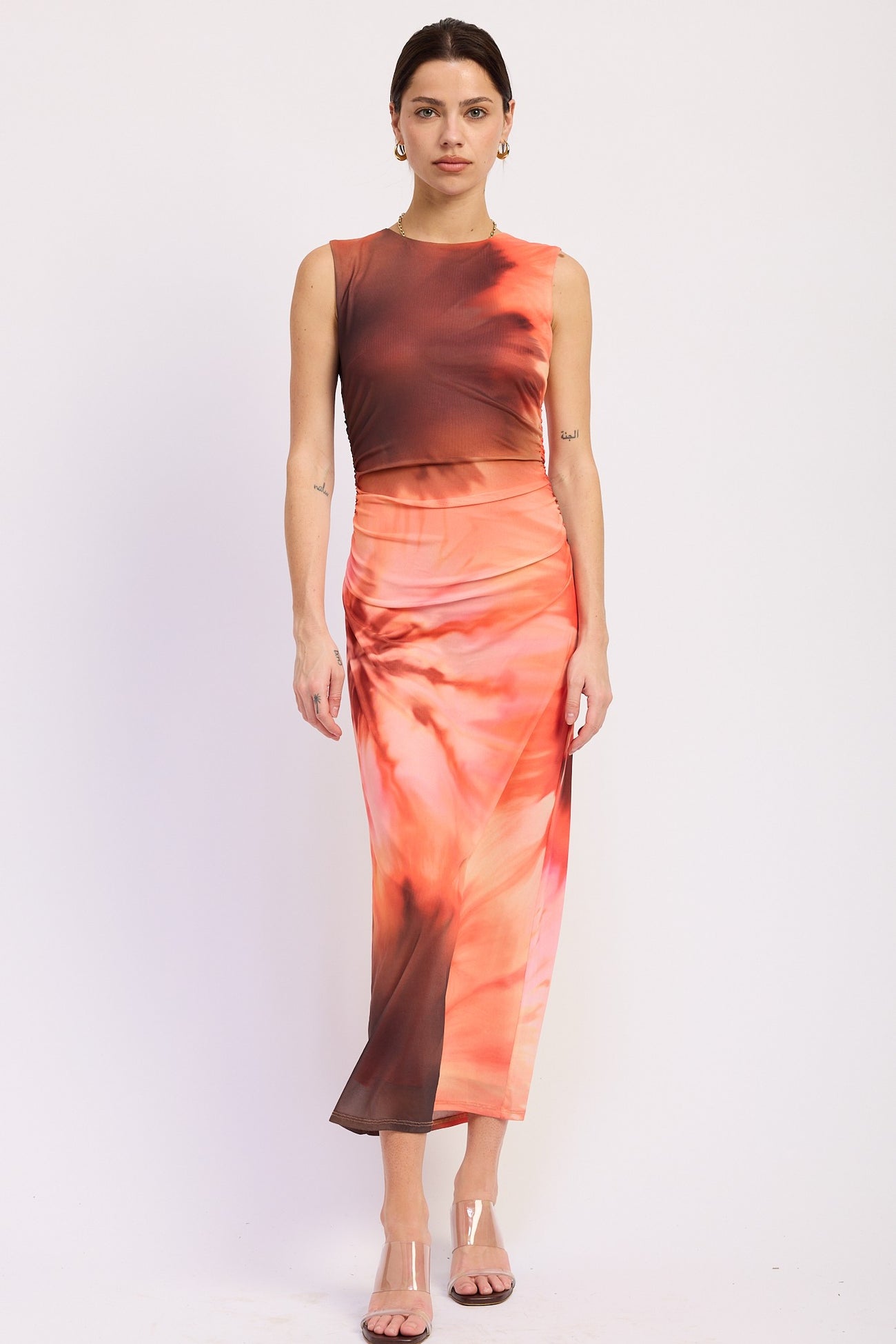 woman wearing a sleeveless tie-dye midi dress featuring orange and brown hues and a fitted silhouette