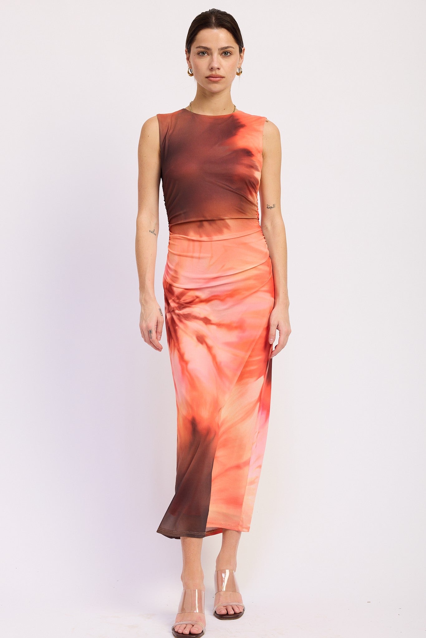 woman wearing a sleeveless tie-dye midi dress featuring orange and brown hues and a fitted silhouette