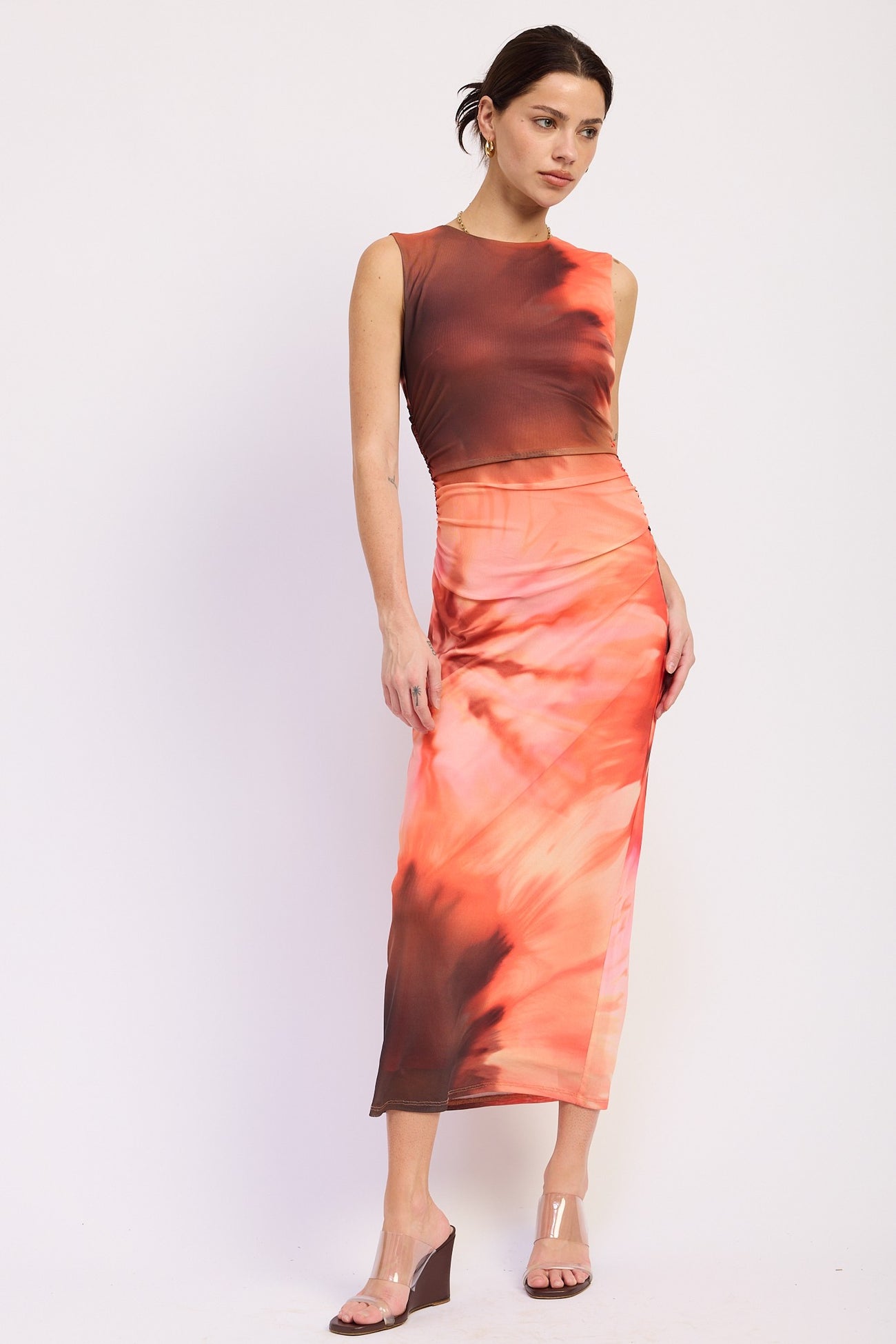 woman wearing a two-piece orange tie-dye crop top and matching midi skirt with a slim fit
