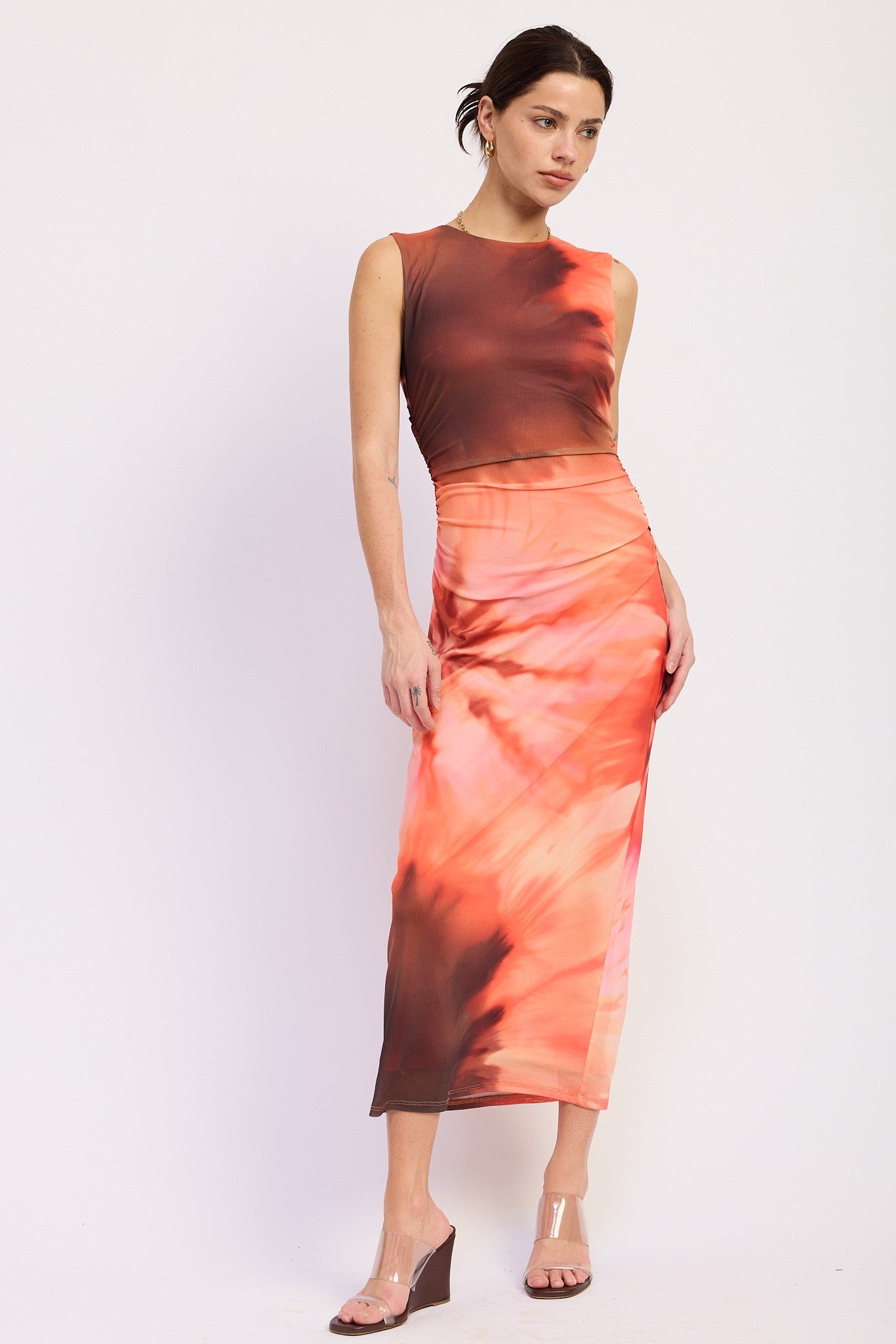 woman wearing a two-piece orange tie-dye crop top and matching midi skirt with a slim fit