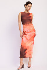 woman wearing a two-piece orange tie-dye crop top and matching midi skirt with a slim fit
