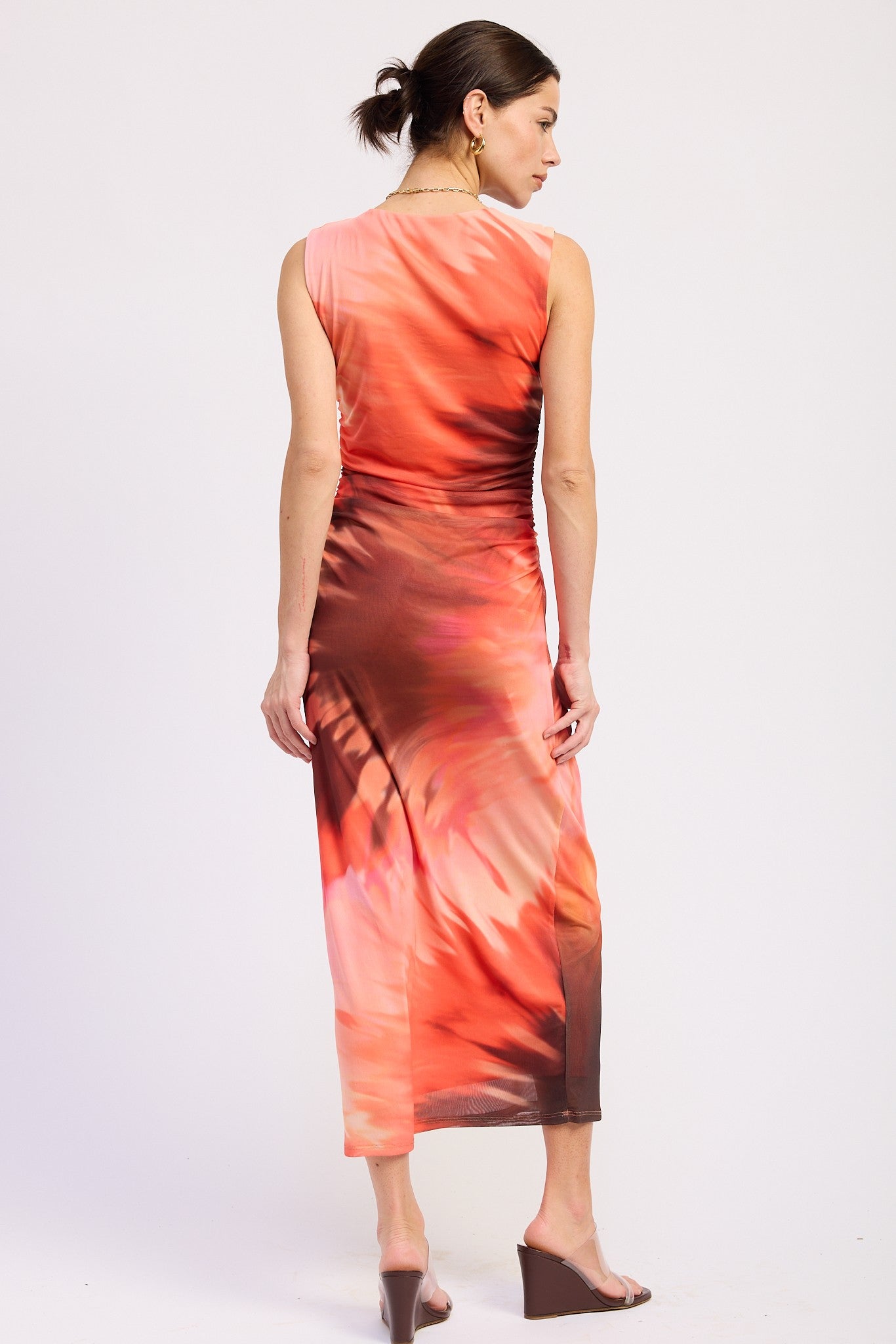 woman wearing a sleeveless maxi dress with a colorful abstract print in shades of pink and brown, seen from the back