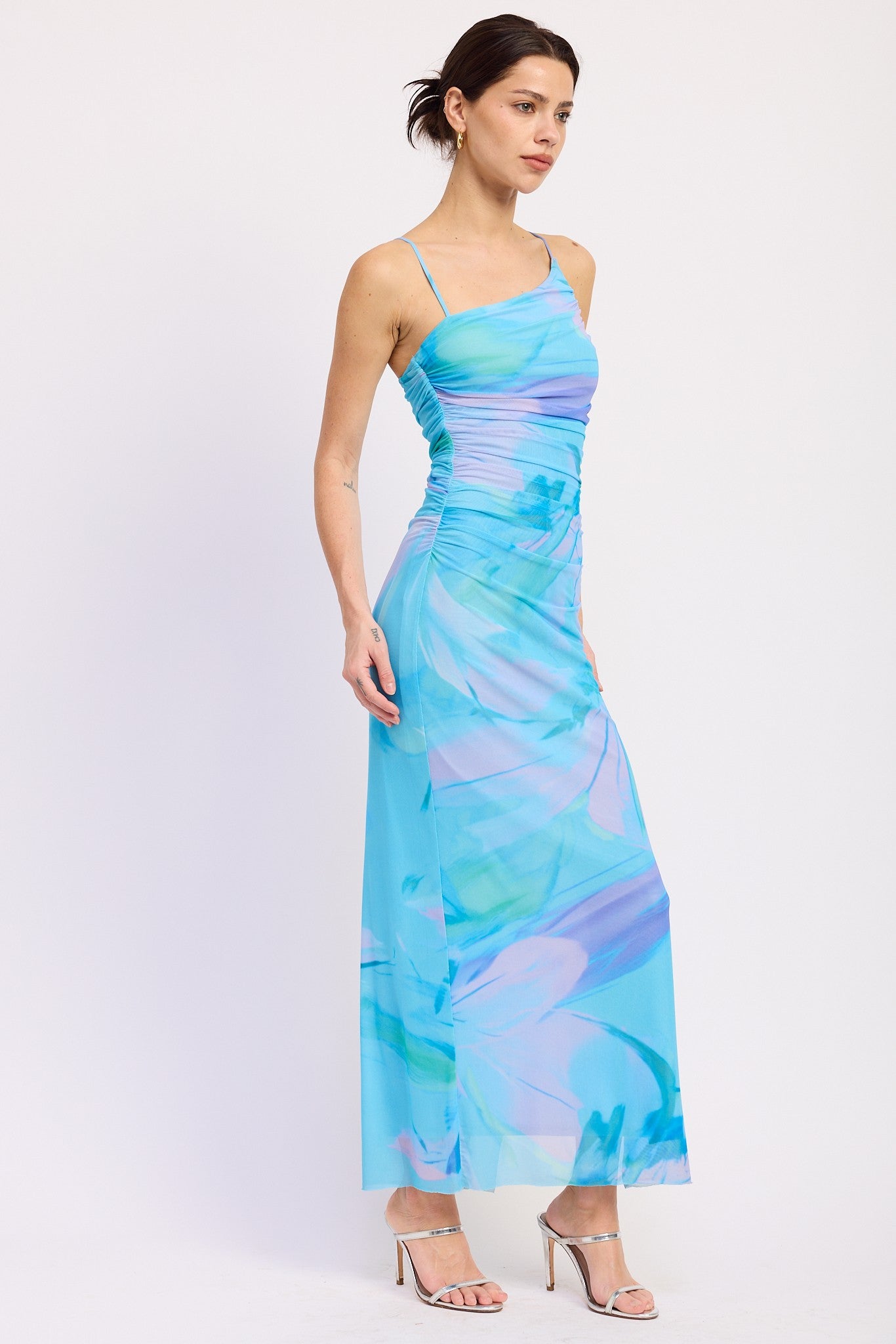 woman wearing a light blue maxi dress with abstract watercolor patterns and thin spaghetti straps