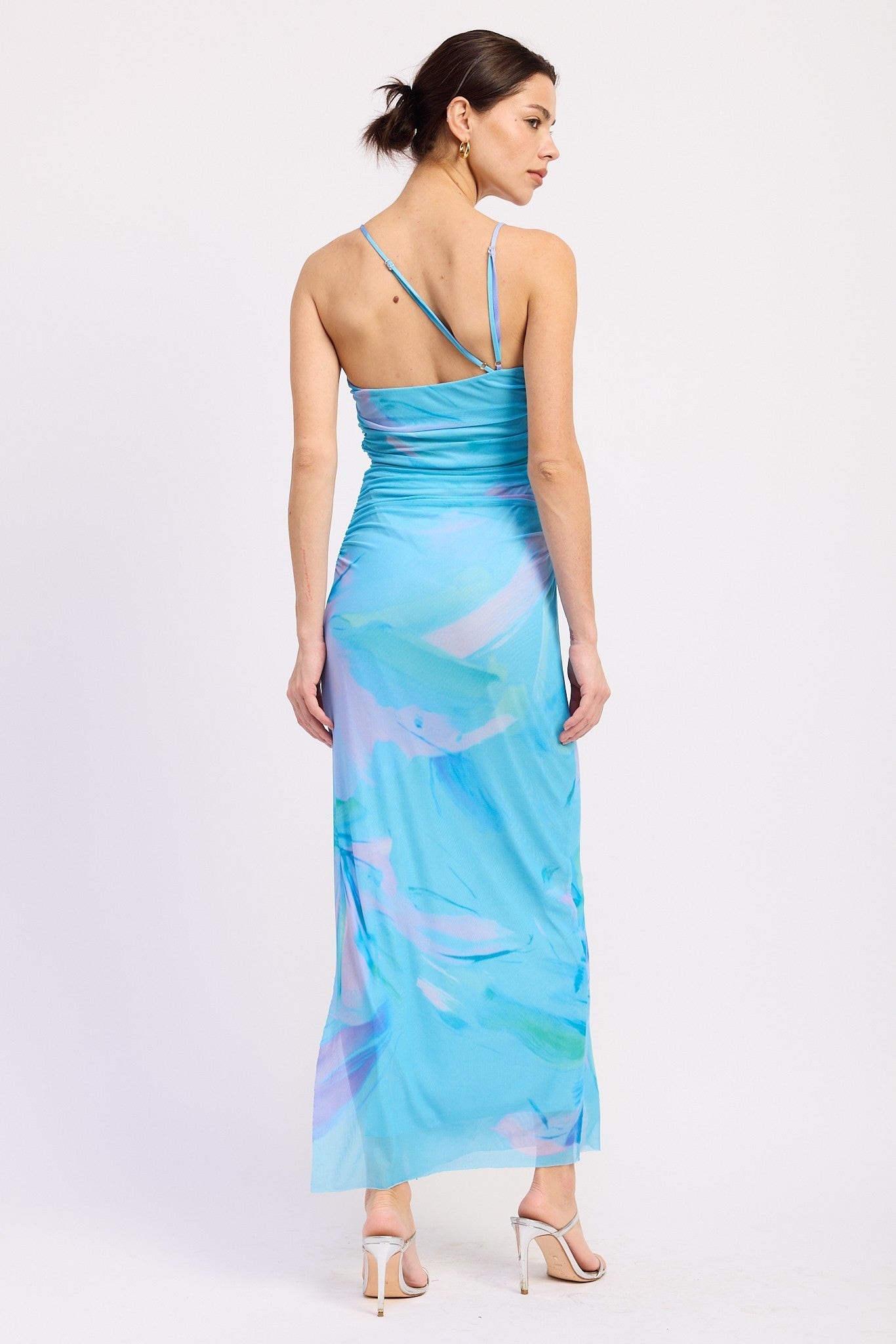 woman wearing a blue maxi dress with abstract pastel print and spaghetti straps, viewed from the back