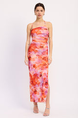 woman wearing a colorful floral maxi dress with a thigh-high slit and spaghetti straps