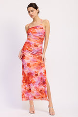 woman wearing a pink and orange floral maxi dress with a side slit and halter neckline