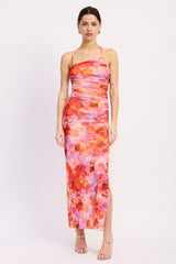 woman wearing a colorful floral maxi dress with a thigh-high slit and spaghetti straps