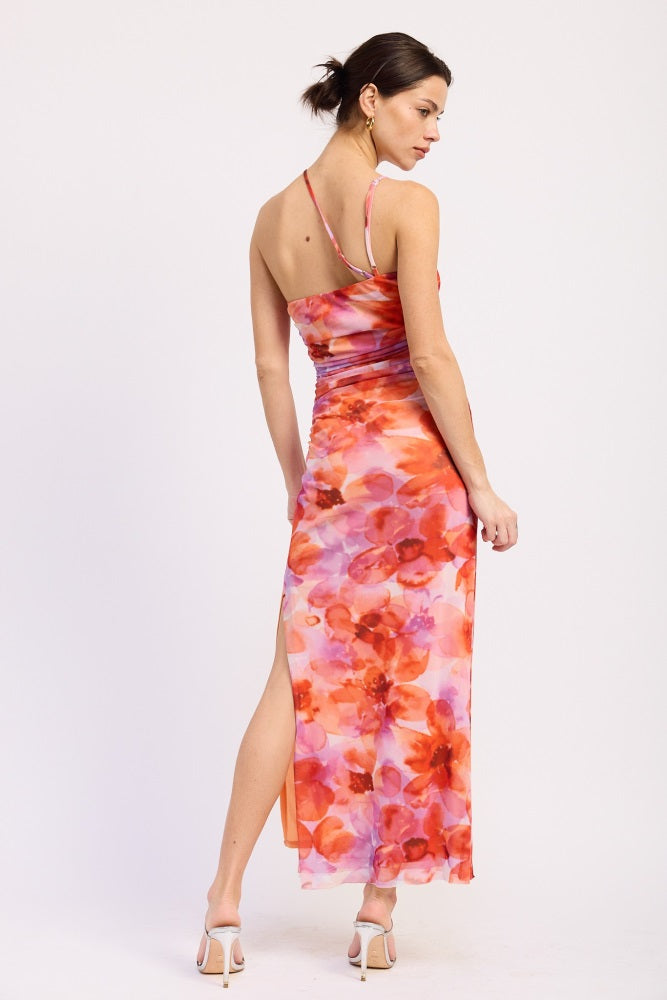woman wearing a floral maxi dress with orange and pink hues and a thigh-high slit, styled with strappy heels