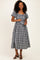 woman wearing a black and white gingham midi dress with puff sleeves and a tie waist detail