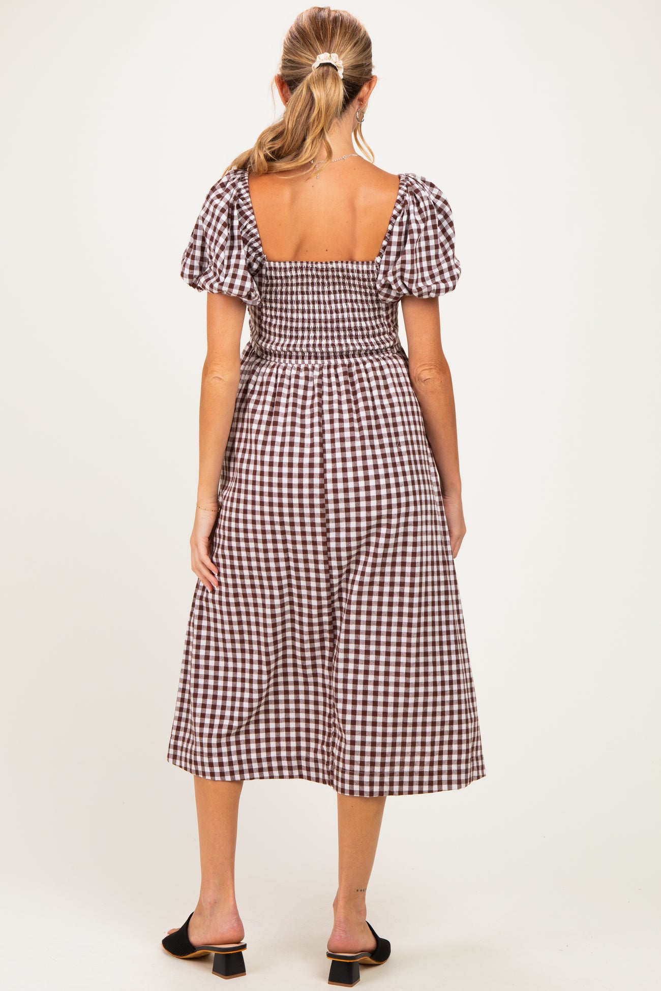 woman wearing a brown and white gingham maternity dress with short puff sleeves and a smocked back
