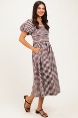 woman wearing a brown and white gingham puff sleeve maxi dress with pockets and sandals
