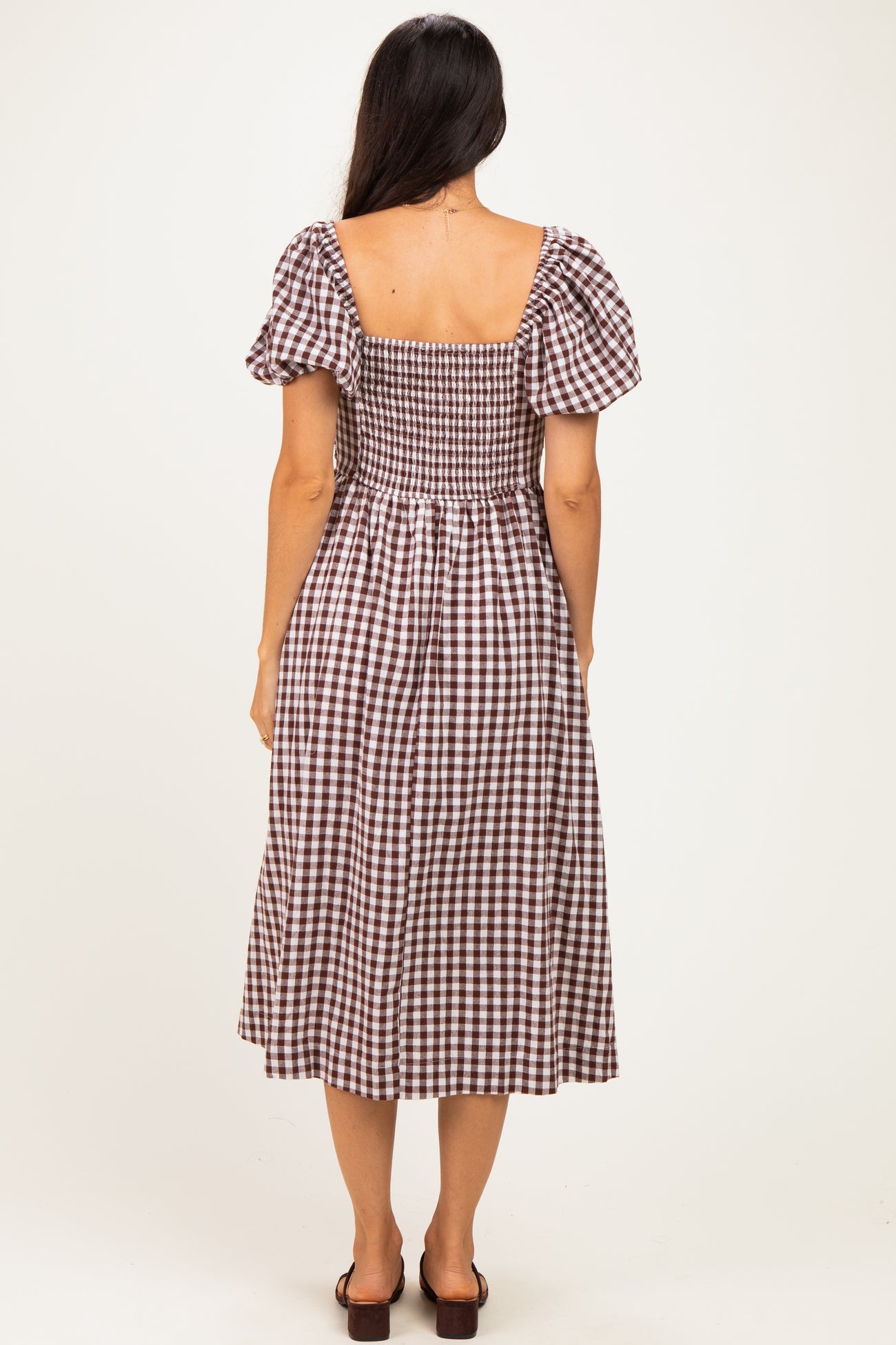 woman wearing a brown and white checkered midi dress with puff sleeves, showing the back view