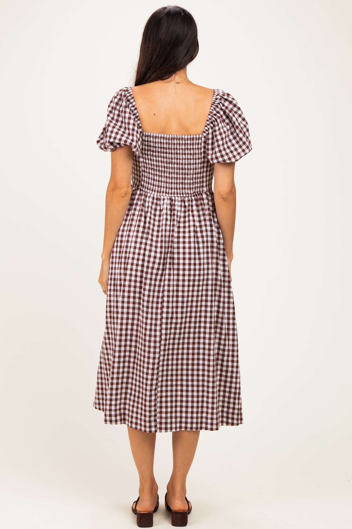 woman wearing a brown and white checkered midi dress with puff sleeves, showing the back view