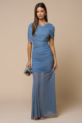 woman wearing a blue ruched evening gown with a sheer overlay and cap sleeves, holding a clutch handbag