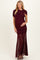woman wearing a burgundy maternity gown with ruched detailing and a sheer long skirt, holding her baby bump