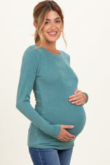 woman wearing a teal ribbed maternity top and holding her baby bump