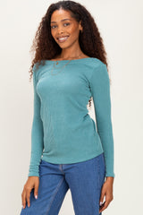 woman wearing a teal ribbed long sleeve top with a boat neckline and smiling at the camera