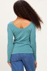 woman wearing a teal ribbed long sleeve top with a wide scoop back and styled with blue jeans