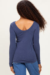 woman wearing a navy blue ribbed long sleeve top with a scooped back and styled with denim jeans