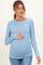 woman wearing a light blue ribbed long sleeve maternity top and holding her baby bump