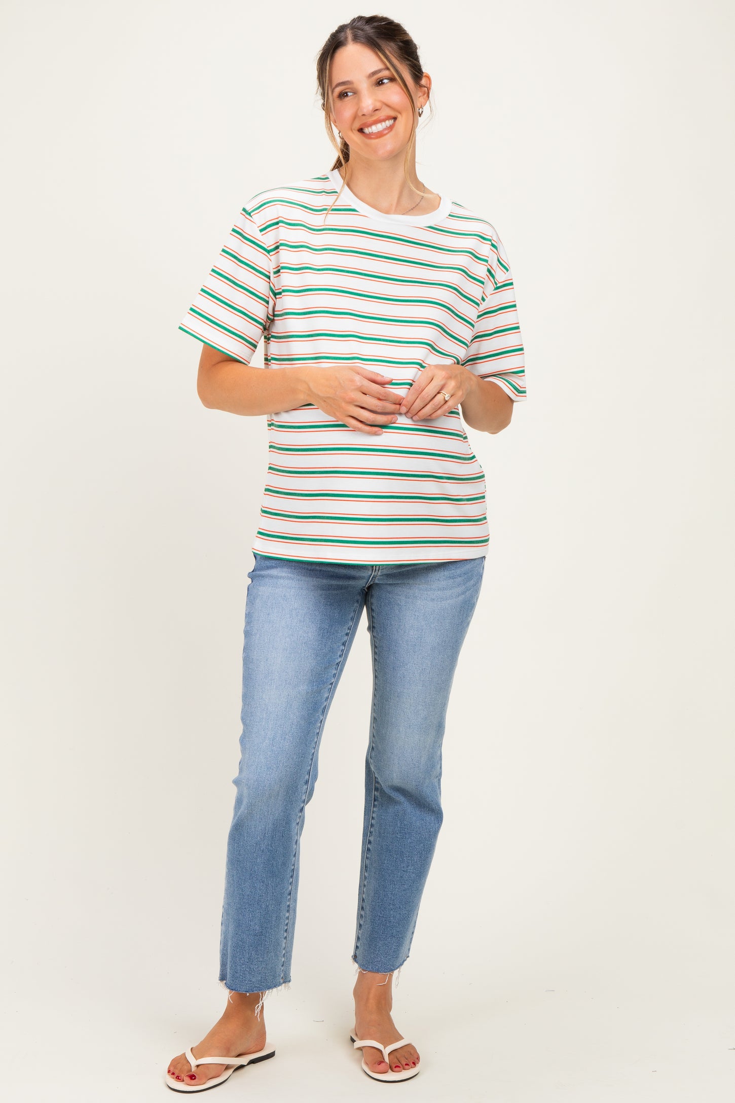 woman wearing a striped maternity top with short sleeves and a relaxed fit, paired with blue jeans