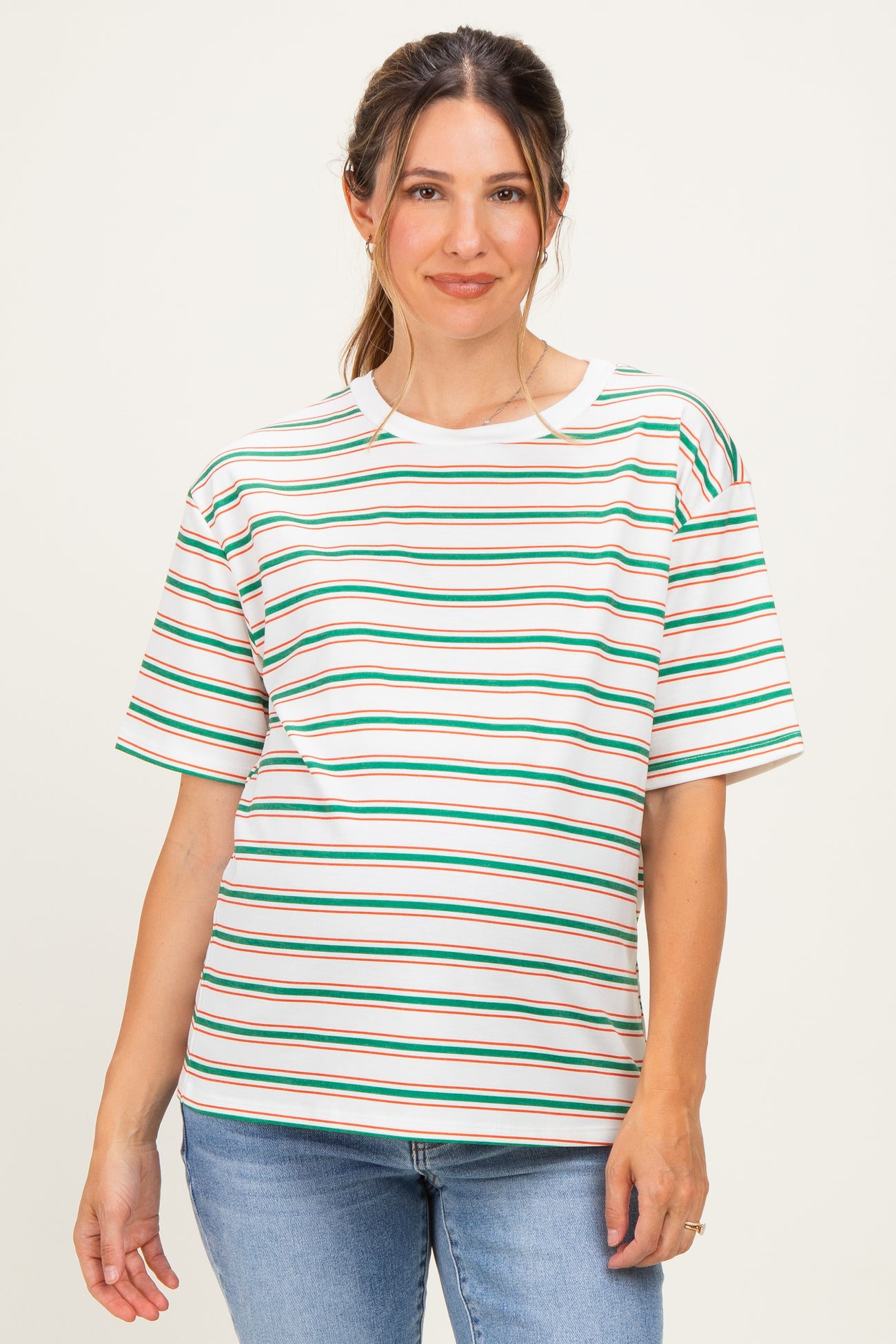 woman wearing a striped maternity top with green, red, and white stripes and a relaxed fit