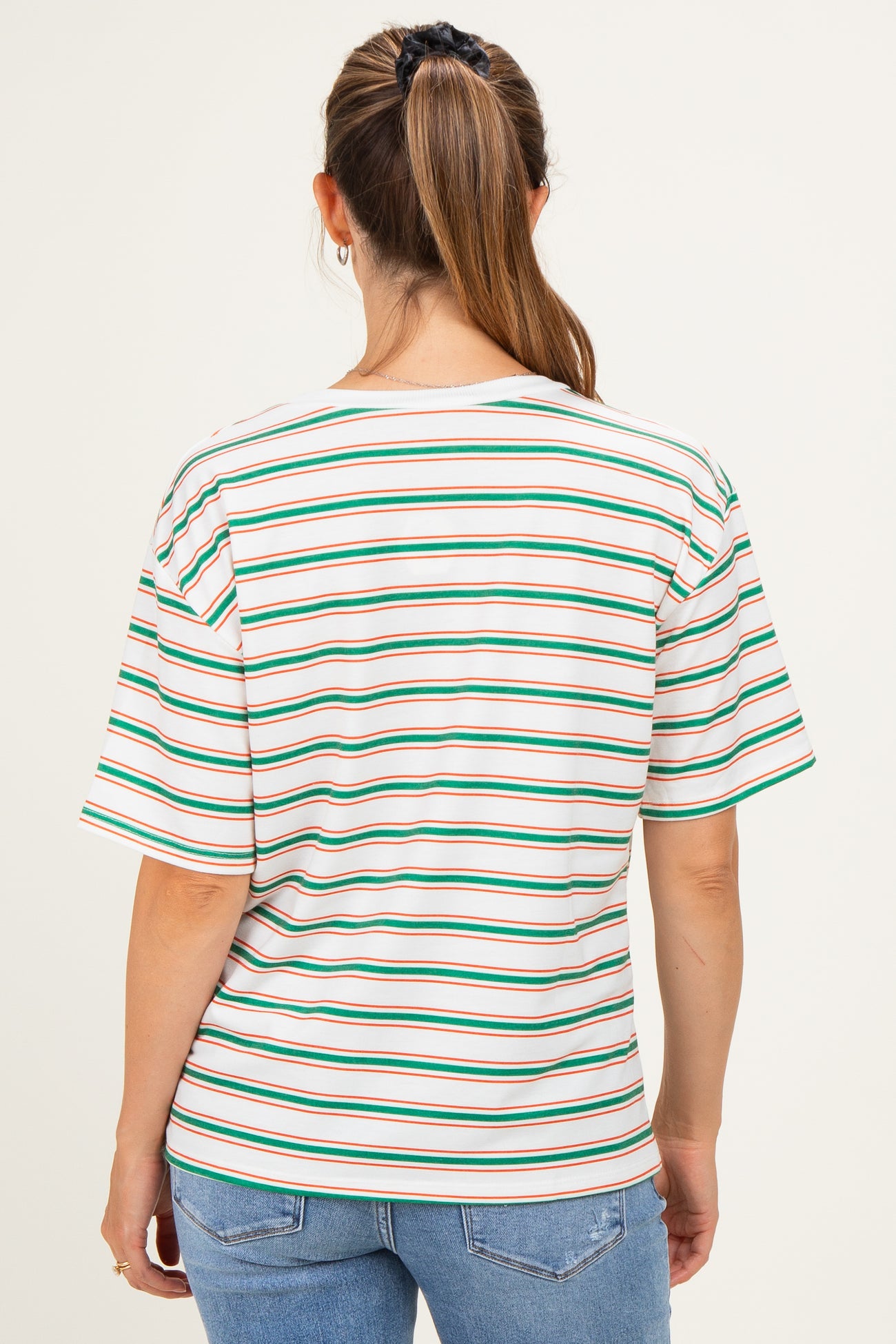woman wearing a striped maternity t-shirt in pastel colors, featuring short sleeves and a relaxed fit, seen from the back