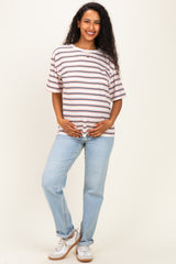 woman wearing a striped maternity t-shirt and light blue jeans, gently holding her baby bump