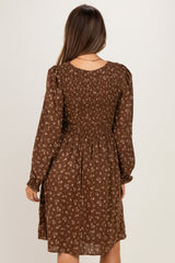 woman wearing a brown floral smocked maternity dress with long sleeves and a relaxed fit from the back