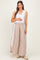 woman wearing a white tank top and striped maternity pants with eyelet detail, holding her baby bump