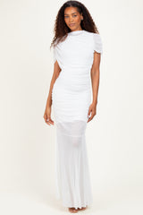 woman wearing a white ruched dress with short sleeves and a sheer bottom, standing against a plain background