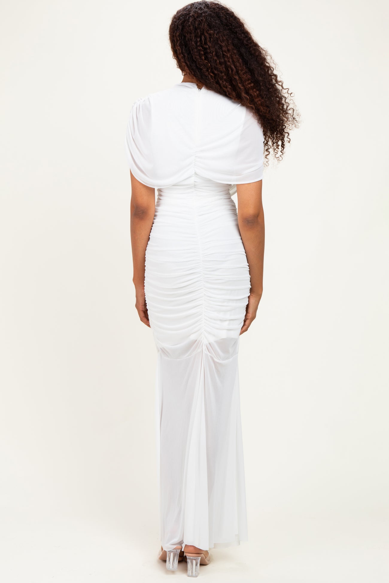 woman wearing a white gathered maxi dress with short sleeves and a fitted silhouette from the back