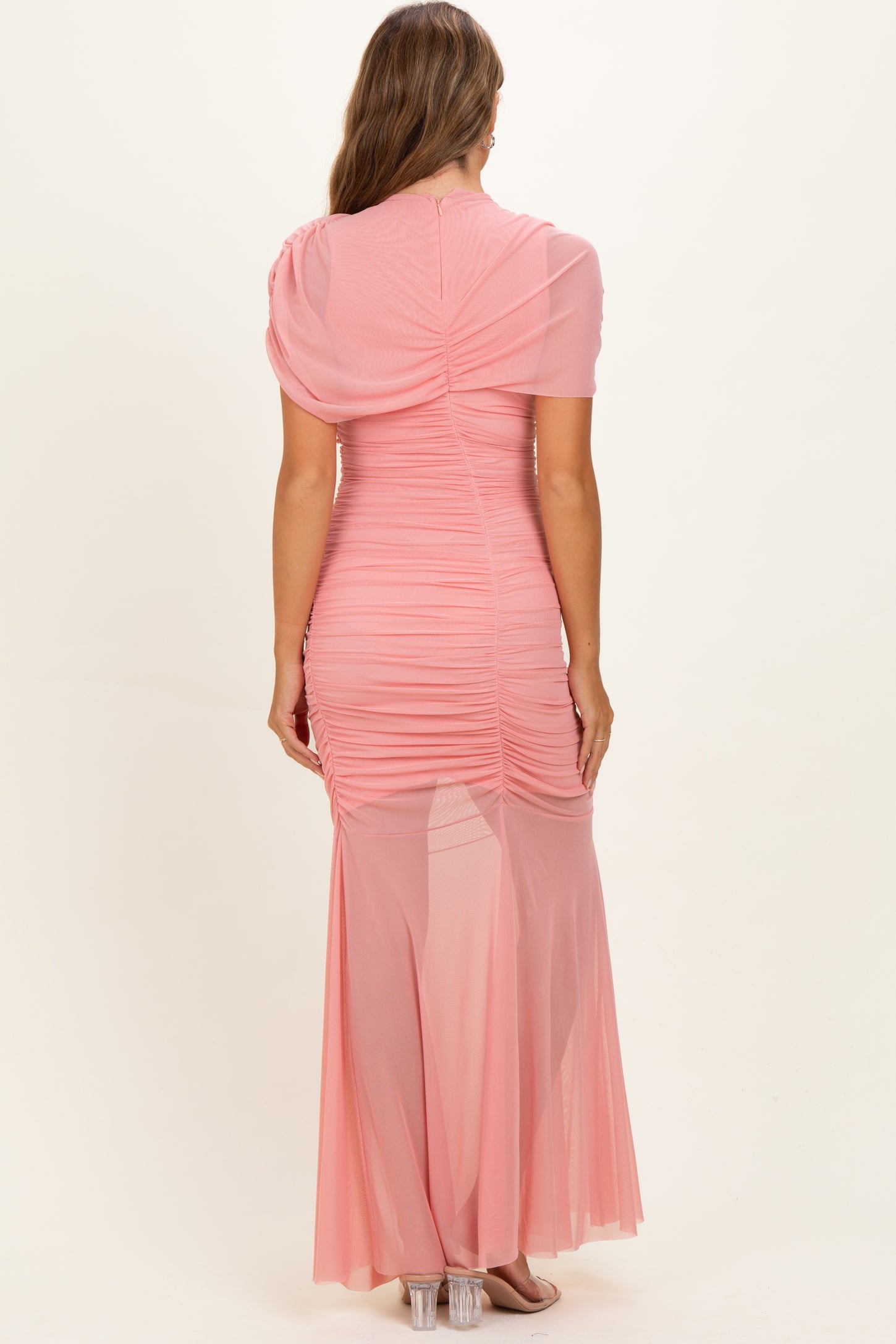 woman wearing a light pink ruched maternity gown with short sleeves and a flowing skirt, back view