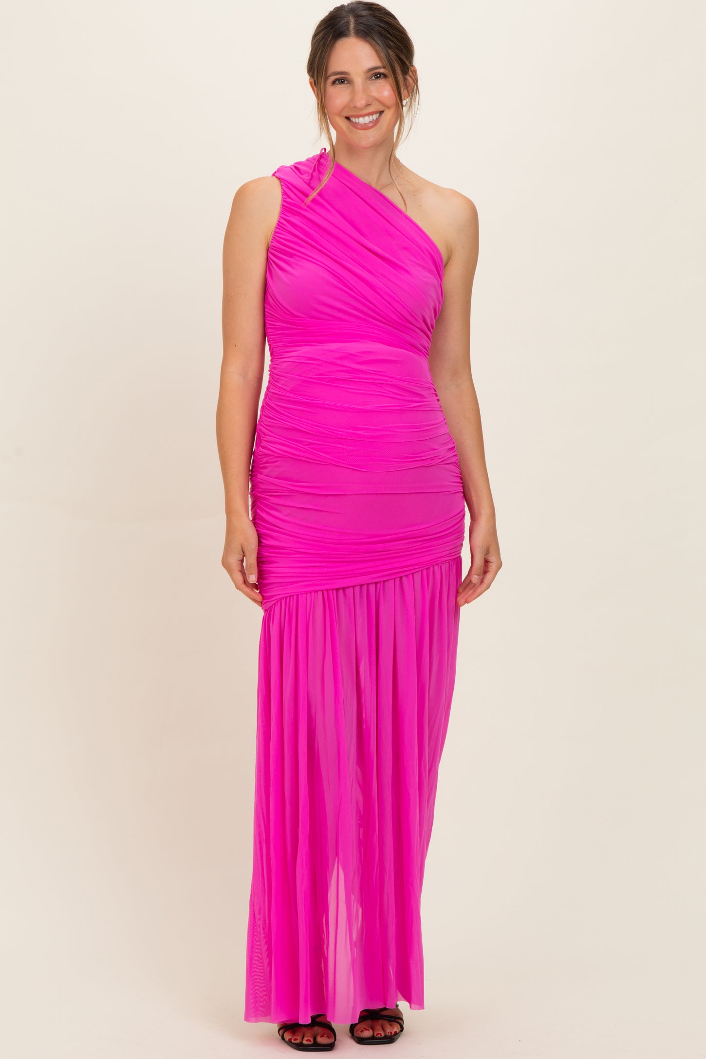 woman wearing a vibrant pink one-shoulder maternity dress with ruching and a flowing skirt