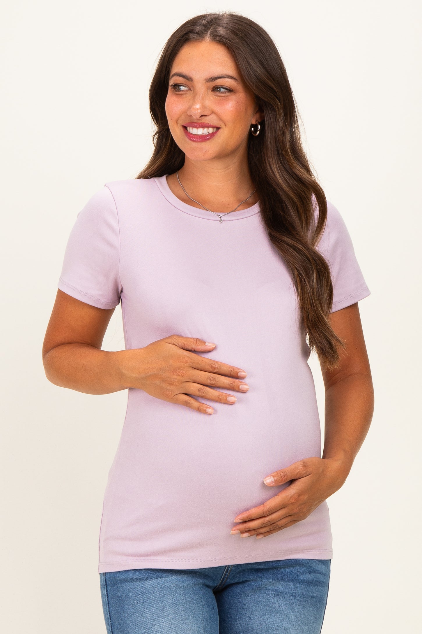 woman wearing a light purple maternity top and holding her baby bump