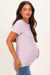 woman wearing a light purple short sleeve maternity top and cradling her baby bump