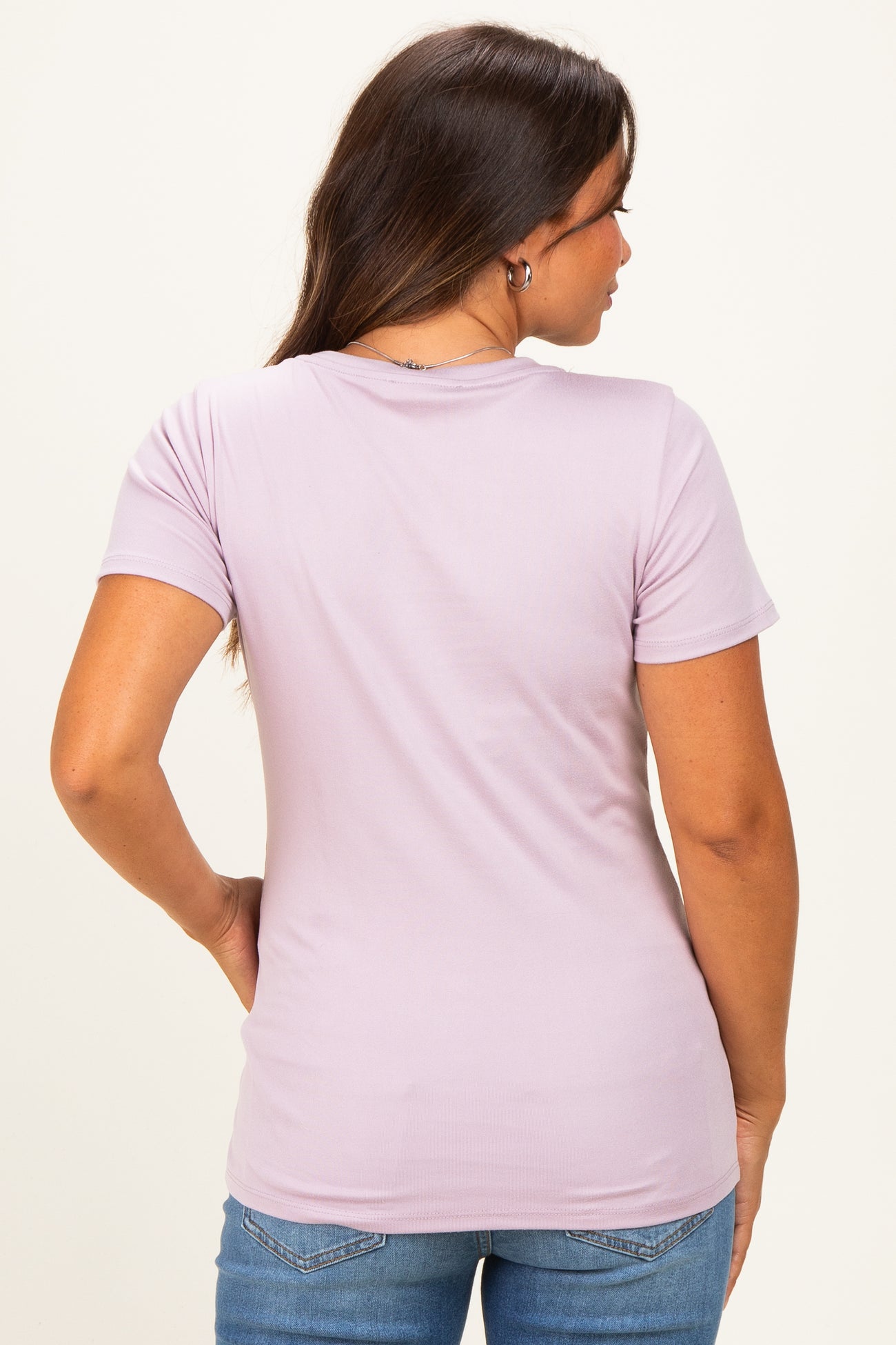 woman wearing a lilac short sleeve maternity top, showing a casual back view