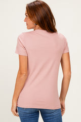 woman wearing a light pink short sleeve top, seen from the back, paired with blue jeans