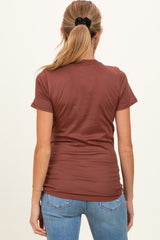 woman wearing a rust brown short sleeve maternity top, viewed from the back, paired with light blue jeans