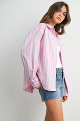 woman wearing a pink and white striped button-up shirt with long sleeves and denim shorts