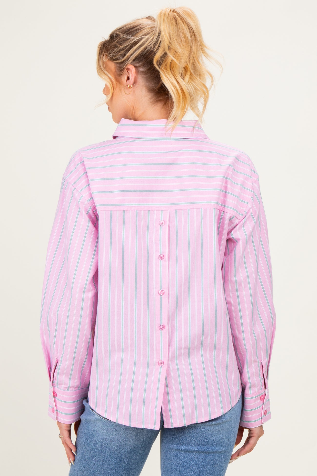 woman wearing a pink and white striped maternity shirt with button details on the back and rolled-up sleeves