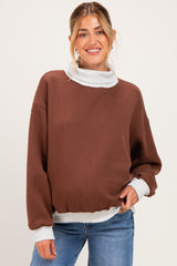 woman wearing a brown maternity sweatshirt with a light gray collar and cuffs, styled casually with jeans