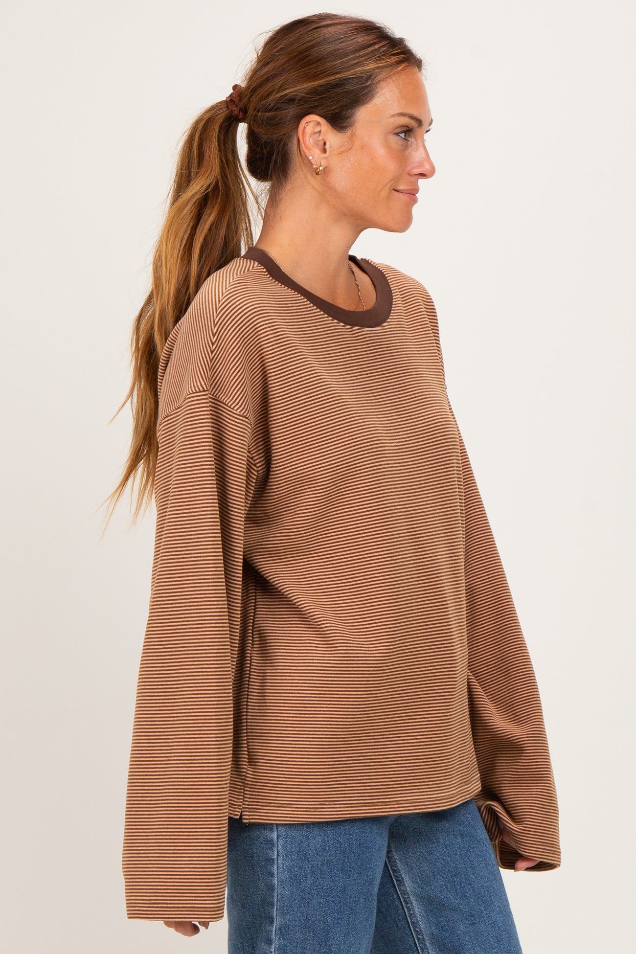 woman wearing a brown striped long sleeve shirt with a ribbed neckline and relaxed fit